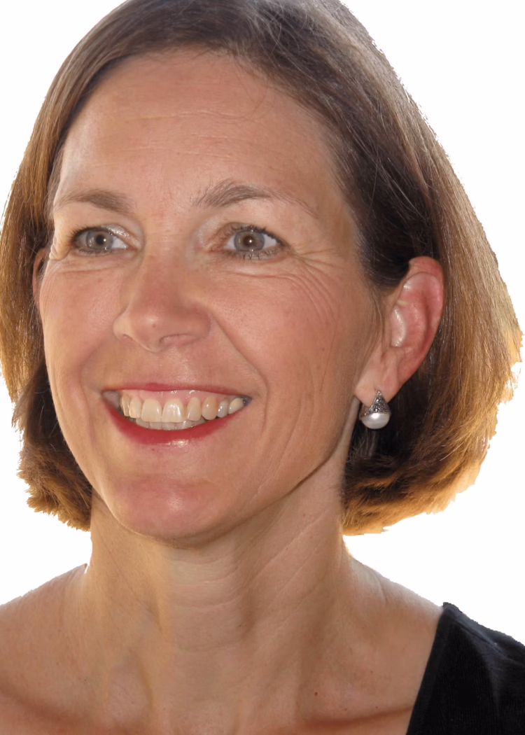 Smiling woman with short brown hair and pearl earrings against a white background