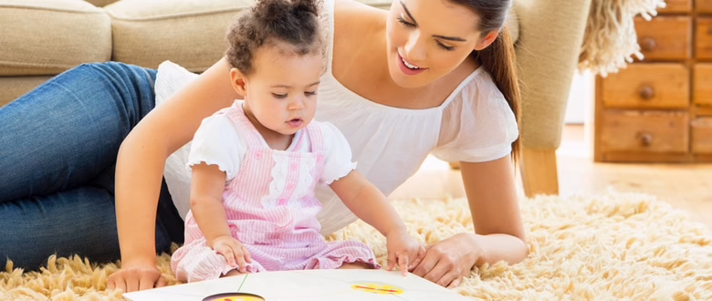 Woman and toddler on a rug, engaging with a colorful book, emphasizing quality early learning