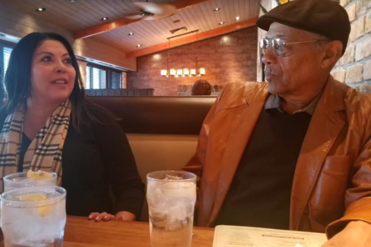 Two people sitting in a restaurant booth, engaged in conversation, with glasses of water on the table