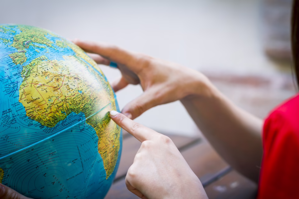 Hands pointing at a globe, highlighting Africa, with a focus on learning and education