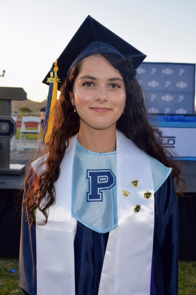 Graduate in cap and gown with a "P" emblem, standing outdoors. Arizona FAF$A Challenge and Ask Benji support students