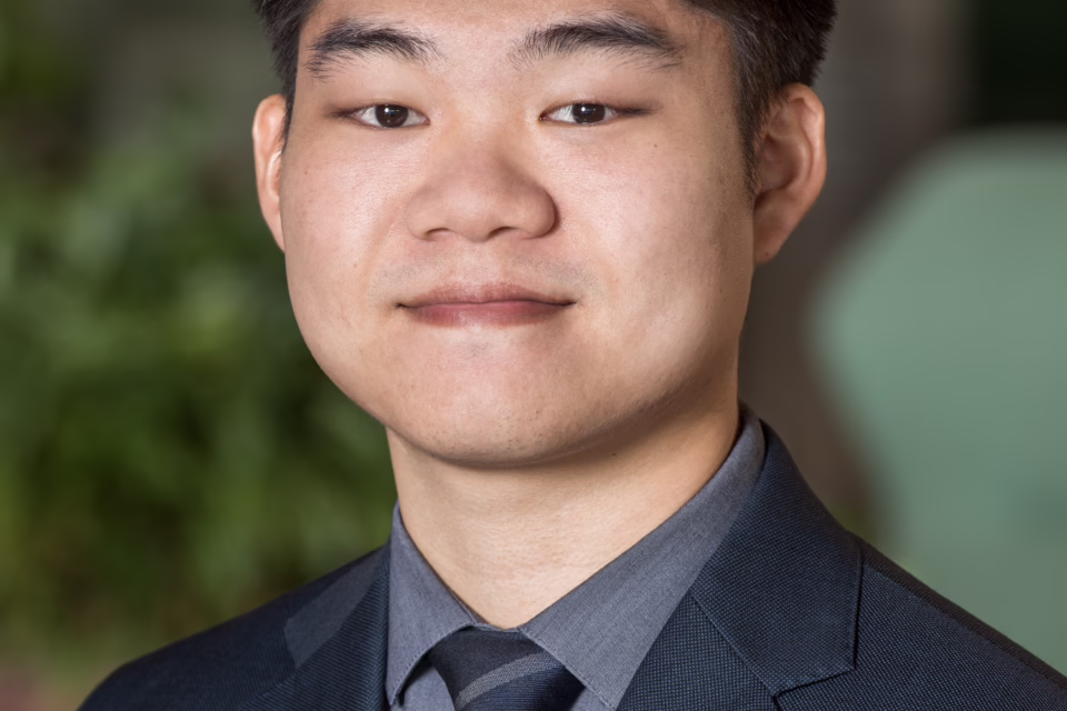 A person in a suit with a star pin on the lapel, standing against a blurred background