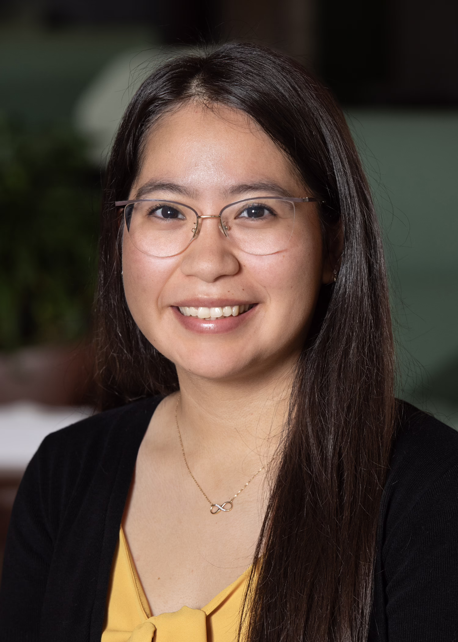 Smiling woman with glasses and long hair, wearing a yellow top and black cardigan, related to Arizona education